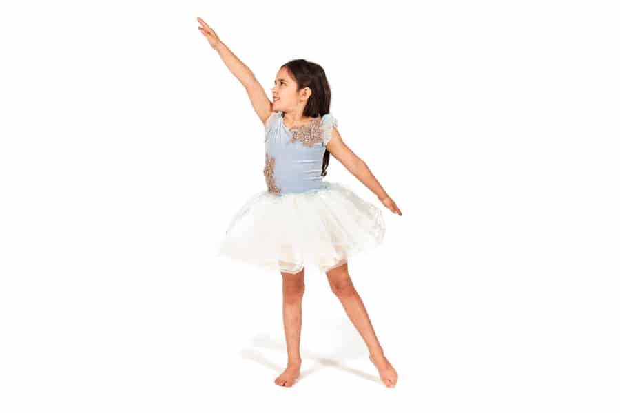 One young dancer reaching her left arm high up.