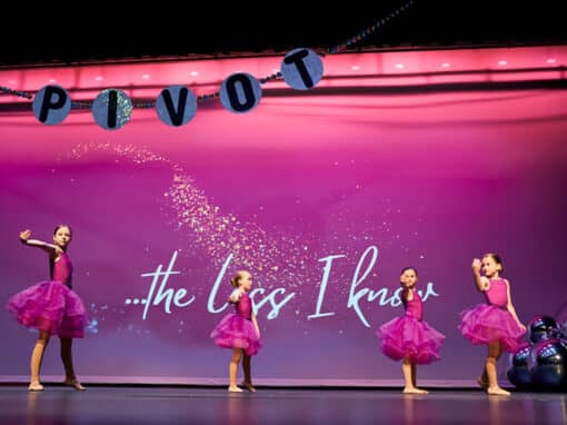 Four young girls with pink dresses are performing on stage. Four young girls with pink dresses are performing on stage.