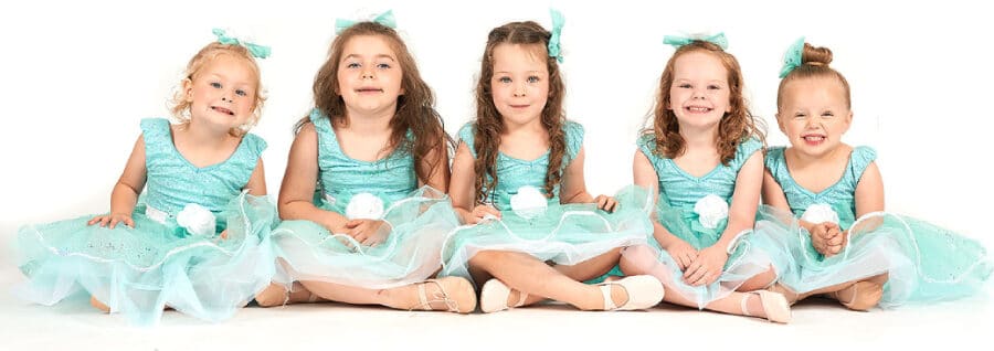 Five cute kids sitting down.